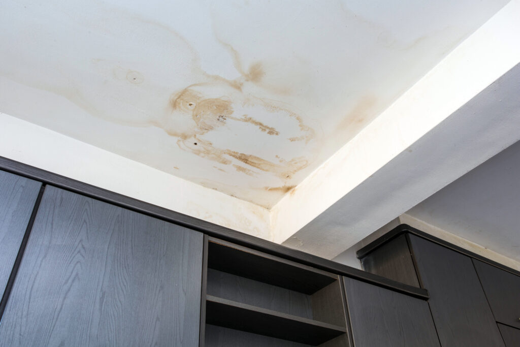 Water damage spreading across a high-rise apartment ceiling from an upper-floor plumbing leak.