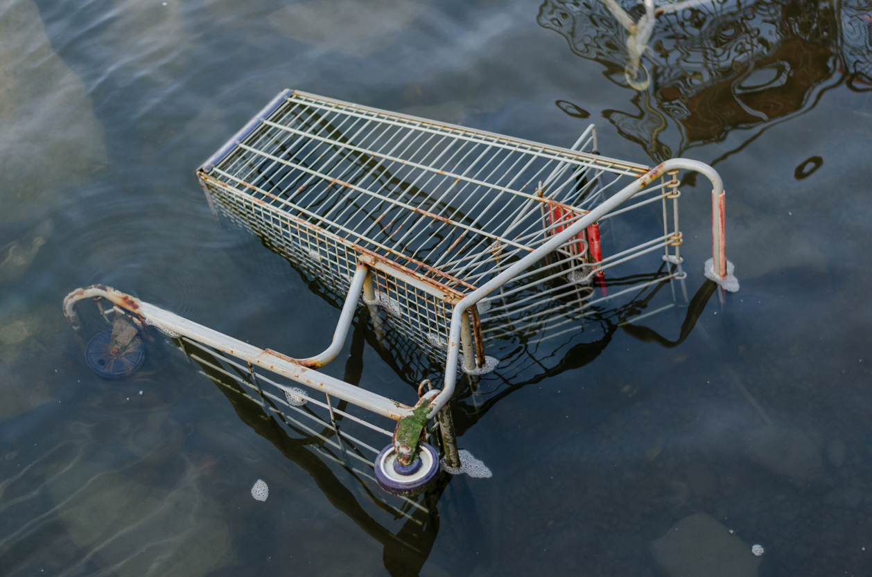 Rusty shopping cart submerged in floodwater, representing retail space water damage and the need for commercial flood cleanup.
