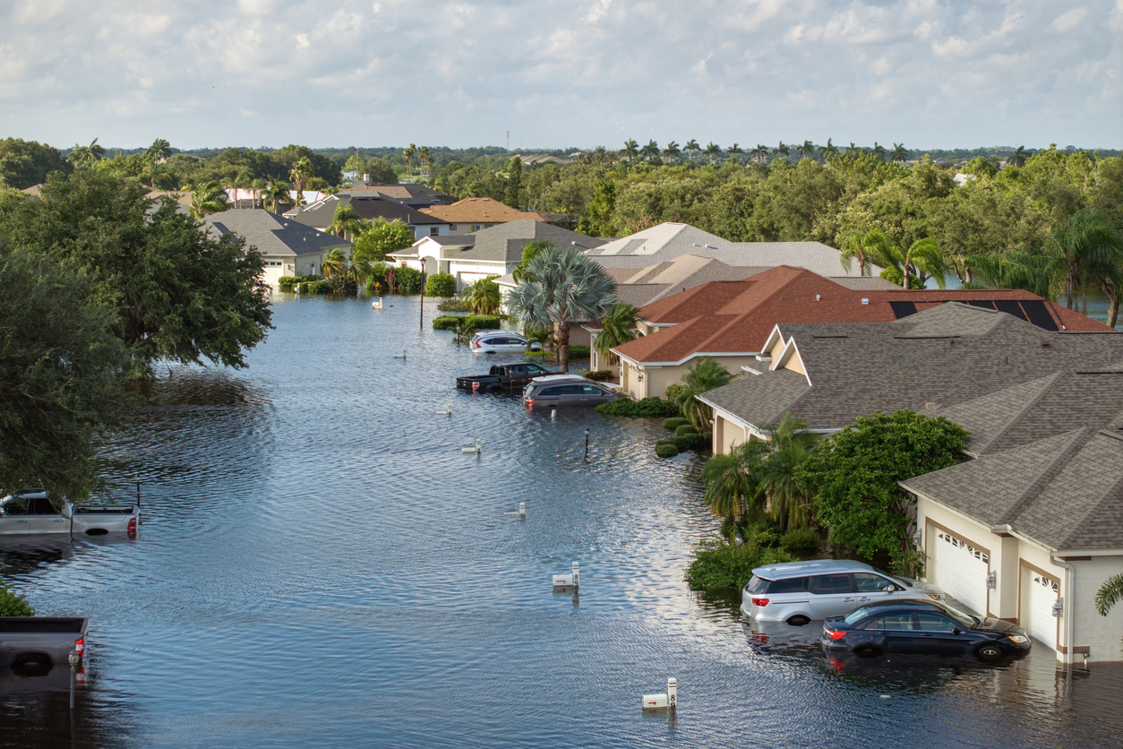 A flooded residential neighborhood with water surrounding homes after a major storm.